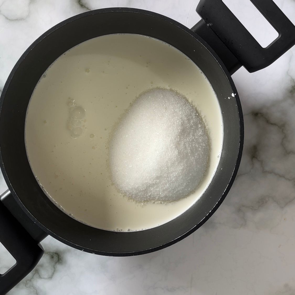Una pentola di liquido bianco con zucchero dentro