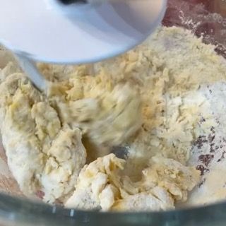 Inizio dell'impasto del babka polacco con aggiunta di acqua a mano.