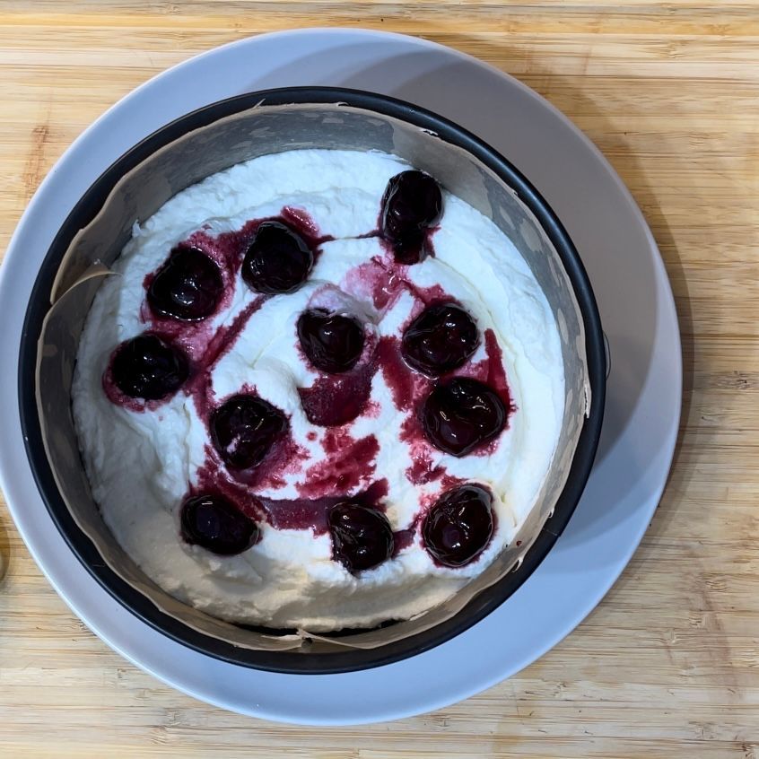 Una ciotola di yogurt con ciliegie sopra su un piatto