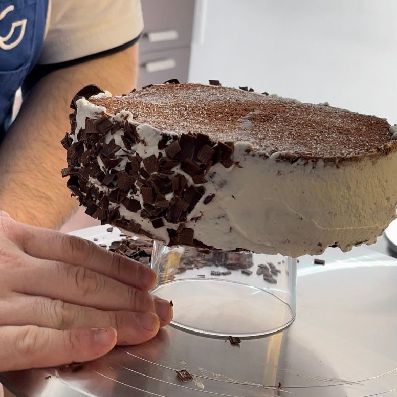 Una persona tiene in mano una torta con delle gocce di cioccolato sopra