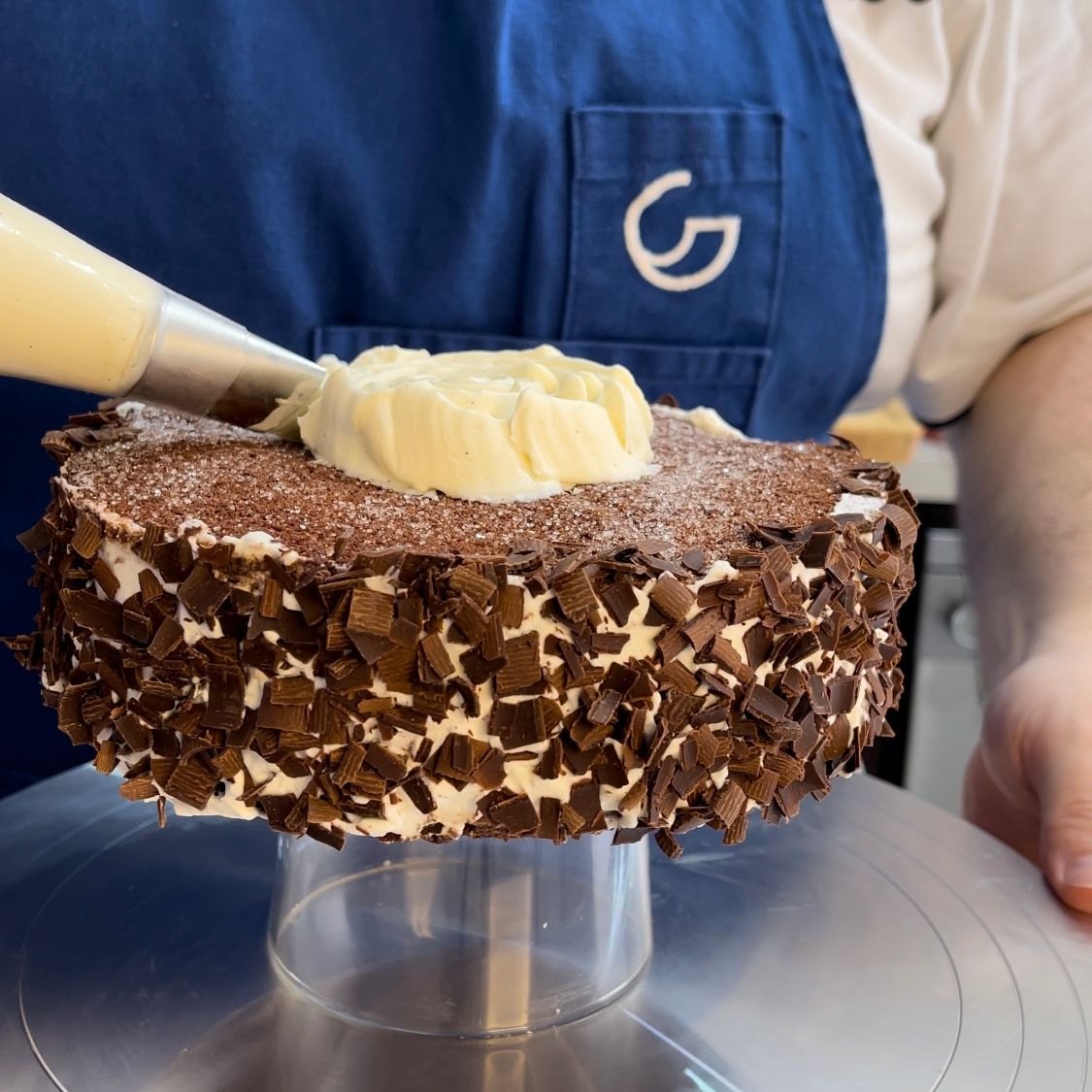 Una persona sta glassando una torta con un ag sul suo grembiule