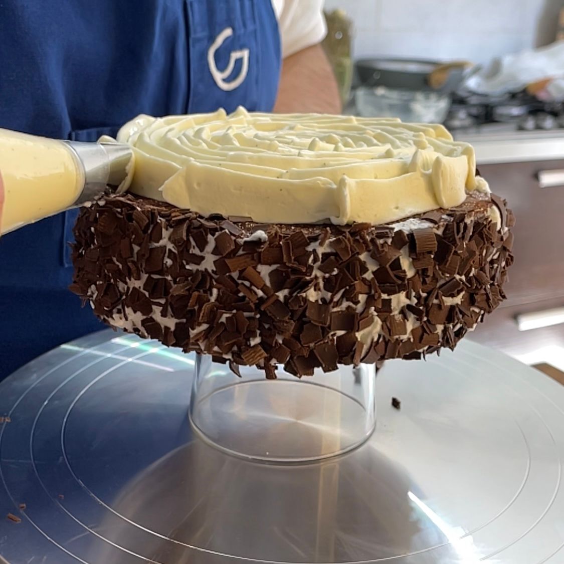 Una persona sta glassando una torta con gocce di cioccolato sopra