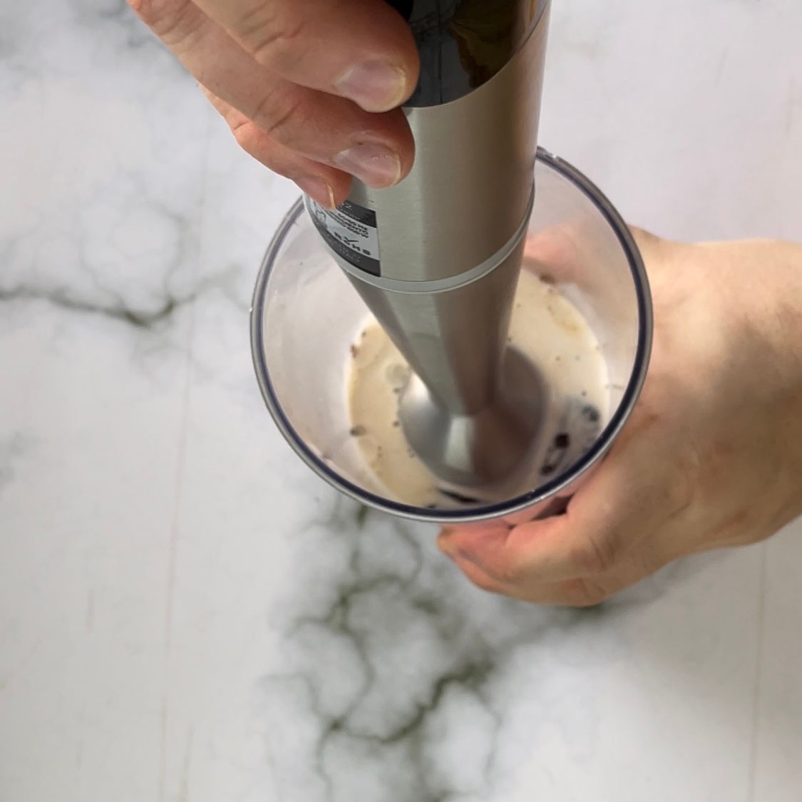 Una persona sta usando un frullatore per mescolare qualcosa in un bicchiere