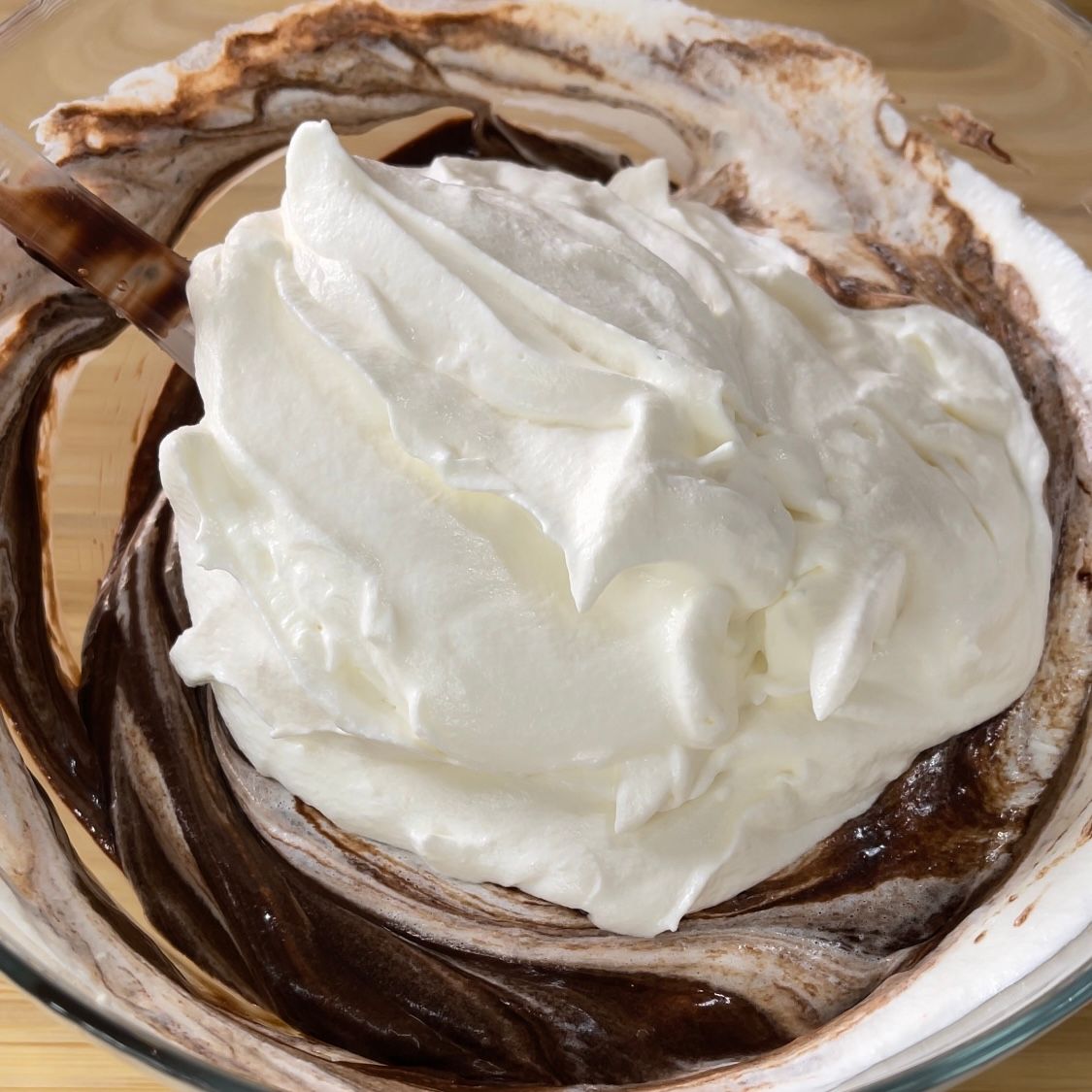 La panna montata viene aggiunta a una ciotola di salsa al cioccolato.