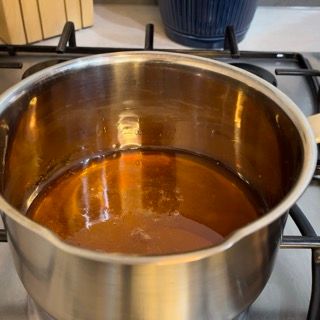 Una pentola piena di liquido marrone è appoggiata sopra un fornello.