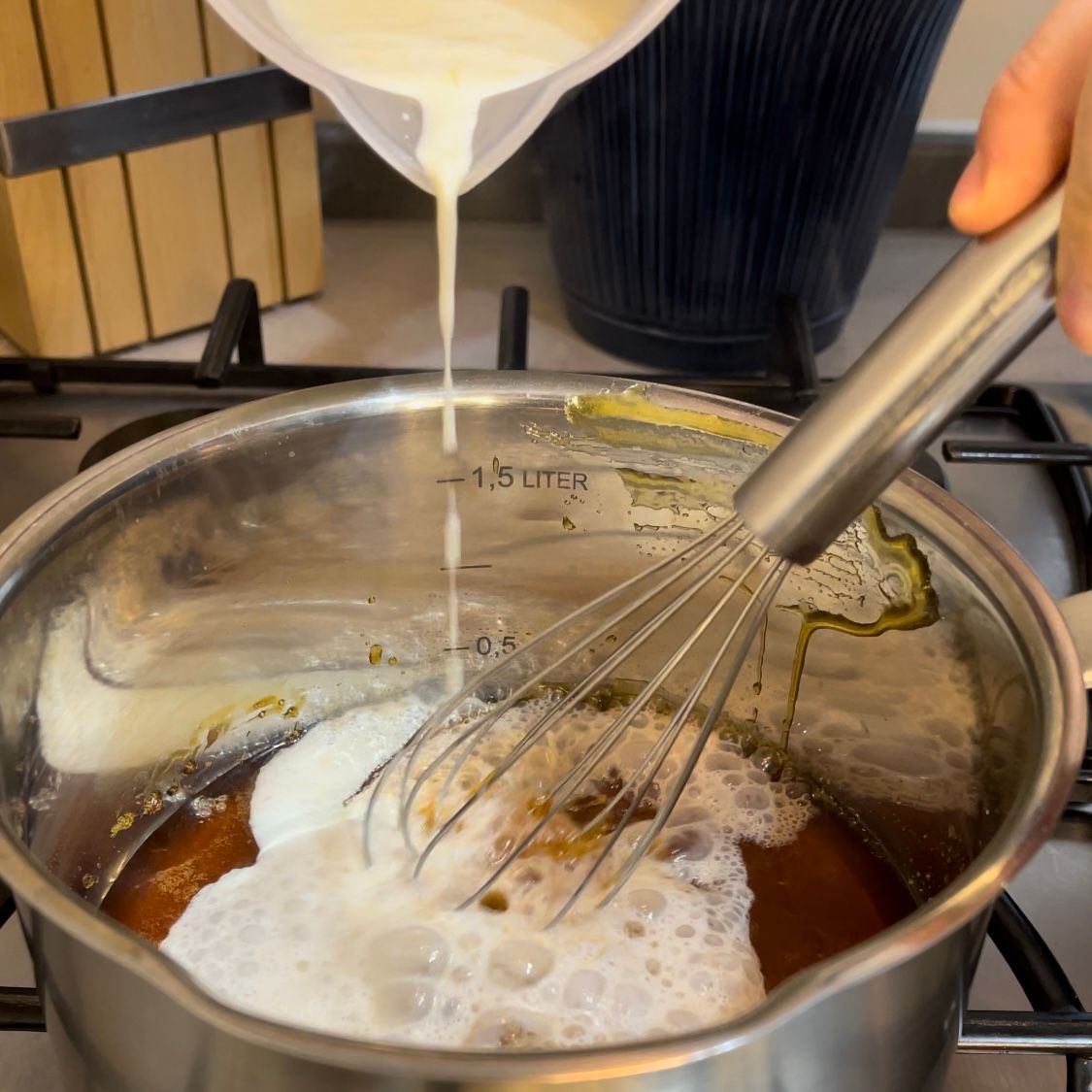 Una persona sta versando del liquido in una pentola con una frusta