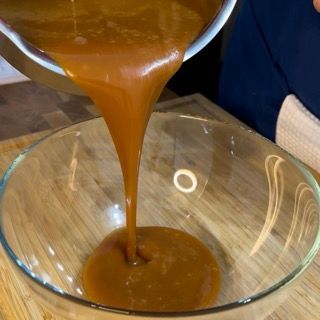 Una salsa viene versata in una ciotola di vetro