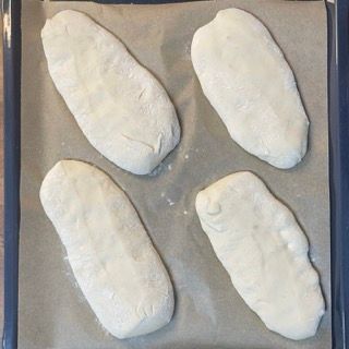 Quattro pagnotte di pane sono appoggiate su un pezzo di carta oleata