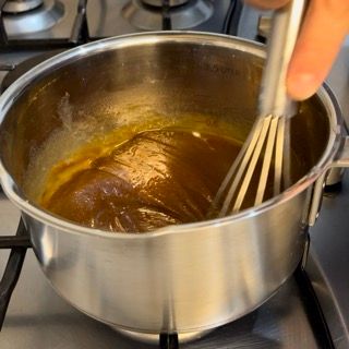 Burro e zucchero che bollono in un pentolino creando una salsa caramellata