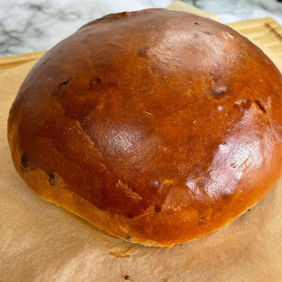 Una pagnotta di pane è appoggiata su un pezzo di carta marrone.
