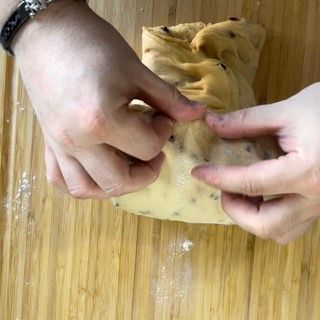 Una persona tiene in mano un pezzo di pasta su un tagliere