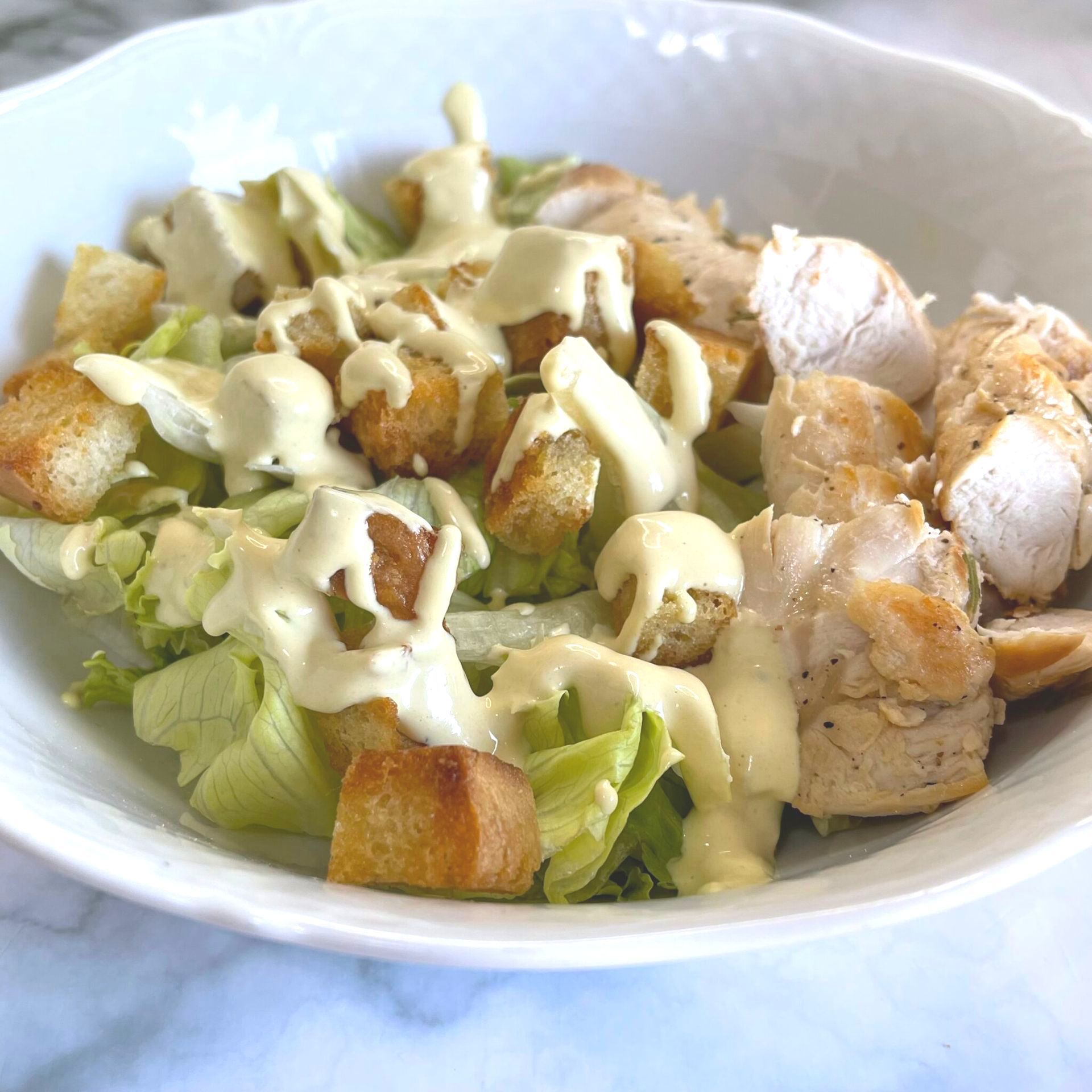Un primo piano di un'insalata con lattuga di pollo e crostini