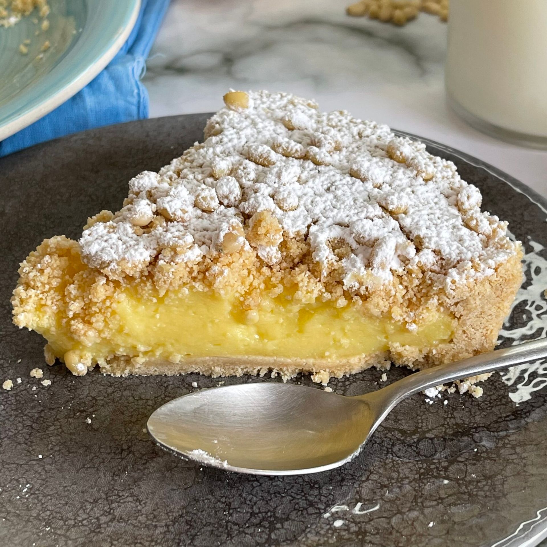 Una fetta di torta con sopra lo zucchero a velo è su un piatto con un cucchiaio.