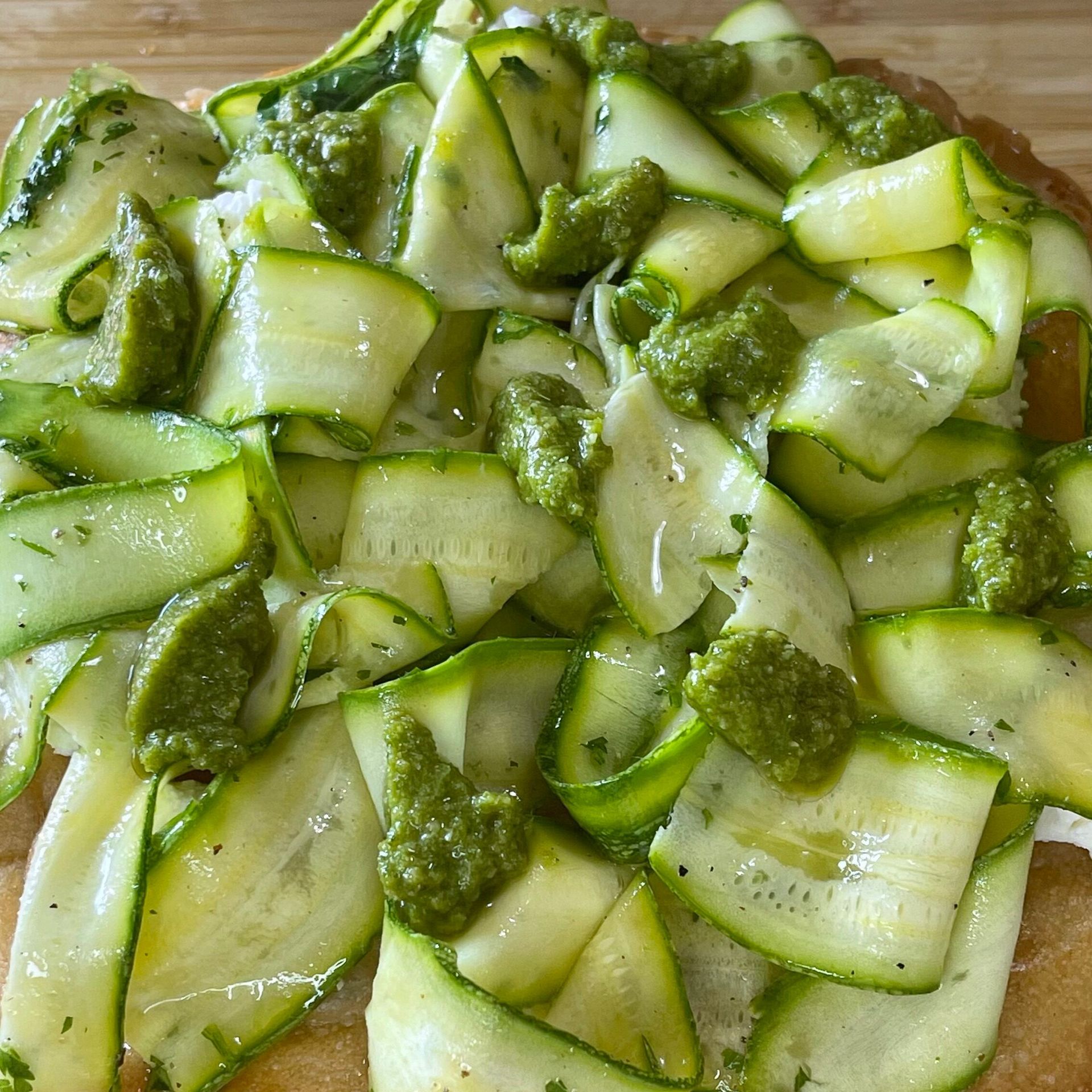 Una pizza con zucchine e pesto sopra