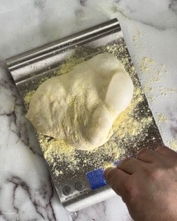 Una persona sta misurando un pezzo di pasta su una bilancia.