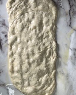 Un pezzo di pasta è appoggiato su una superficie di marmo.