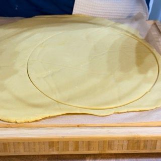 Un pezzo di pasta è appoggiato su un tagliere di legno.