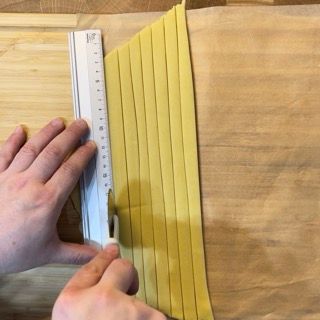 Una persona sta misurando un pezzo di pasta con un righello