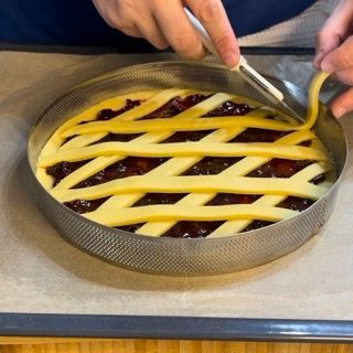 Una persona sta tagliando una torta con una crosta a traliccio