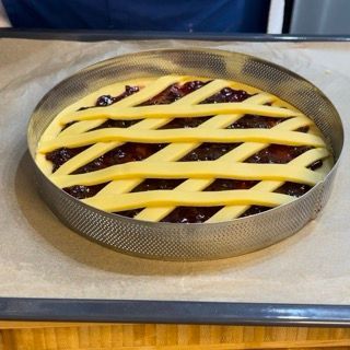 Una torta con una crosta a traliccio è appoggiata su un tavolo