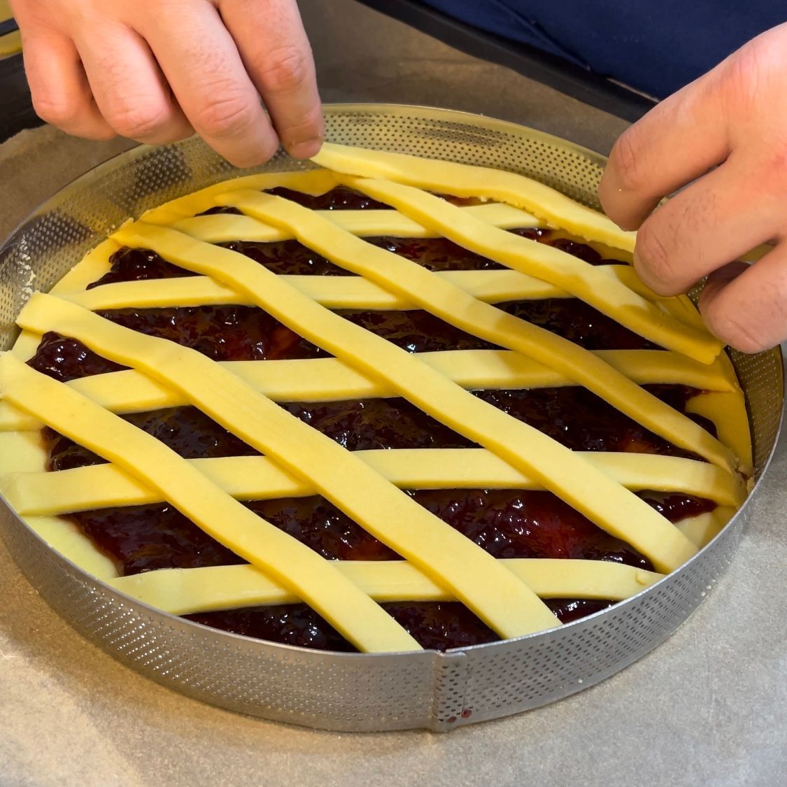 Una persona sta preparando una torta con una crosta a reticolo
