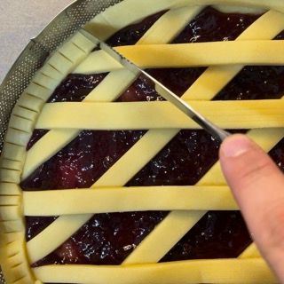 Una persona sta tagliando una torta con una crosta a traliccio