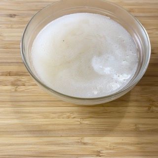 Una ciotola piena di liquido schiumoso è appoggiata su un tavolo di legno.