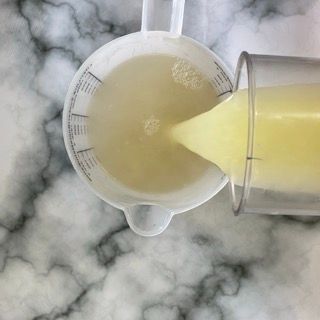 Una brocca di liquido viene versata in un bicchiere.