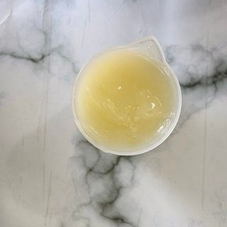 Primo piano di un misurino pieno di liquido giallo su un tavolo.