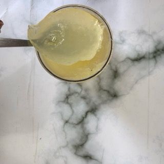 Una persona versa del liquido in un misurino con un cucchiaio.