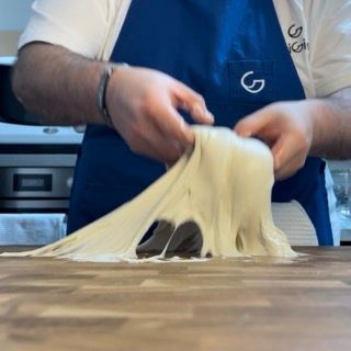 Una persona che indossa un grembiule blu con la lettera g sopra