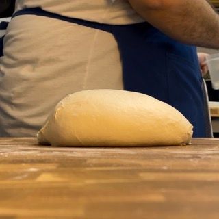 Una palla di pasta è appoggiata su un tavolo di legno