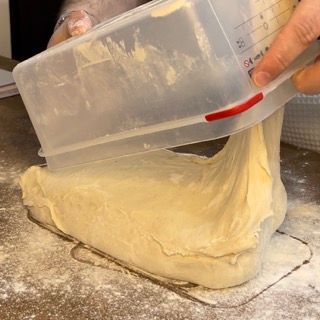 Una persona sta versando l'impasto da una tazza graduata