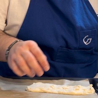 Una persona che indossa un grembiule blu con la lettera g sopra
