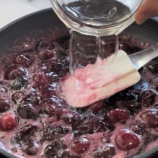Una persona sta versando del liquido in una pentola di ciliegie