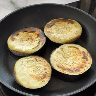Quattro metà di melanzane vengono cotte in una padella