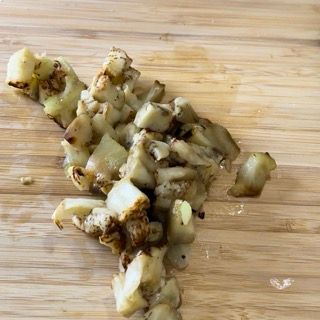 Un tagliere di legno con sopra delle patate tritate