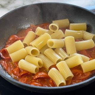 La pasta viene cotta in padella con sugo di pomodoro.