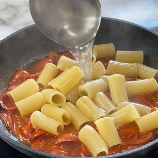 La pasta viene versata in una padella con il sugo di pomodoro