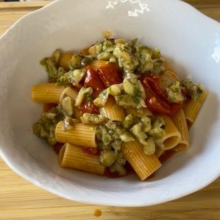 Una ciotola bianca piena di pasta e verdure su un tavolo di legno