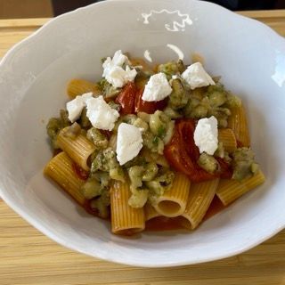 Una ciotola di pasta con pomodori e formaggio sopra
