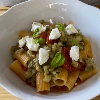 Una ciotola di pasta con verdure e formaggio sopra