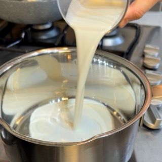 Una persona che versa il latte in una pentola sul fornello