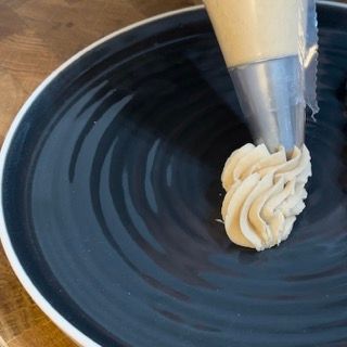Un piatto nero con sopra della panna montata