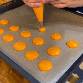 Una persona sta preparando dei biscotti arancioni su una teglia da forno
