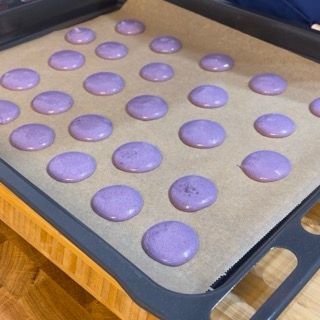 Un vassoio di macarons viola su un pezzo di carta oleata