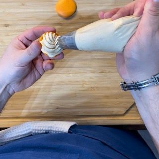 Una persona sta versando la glassa su un piccolo cupcake