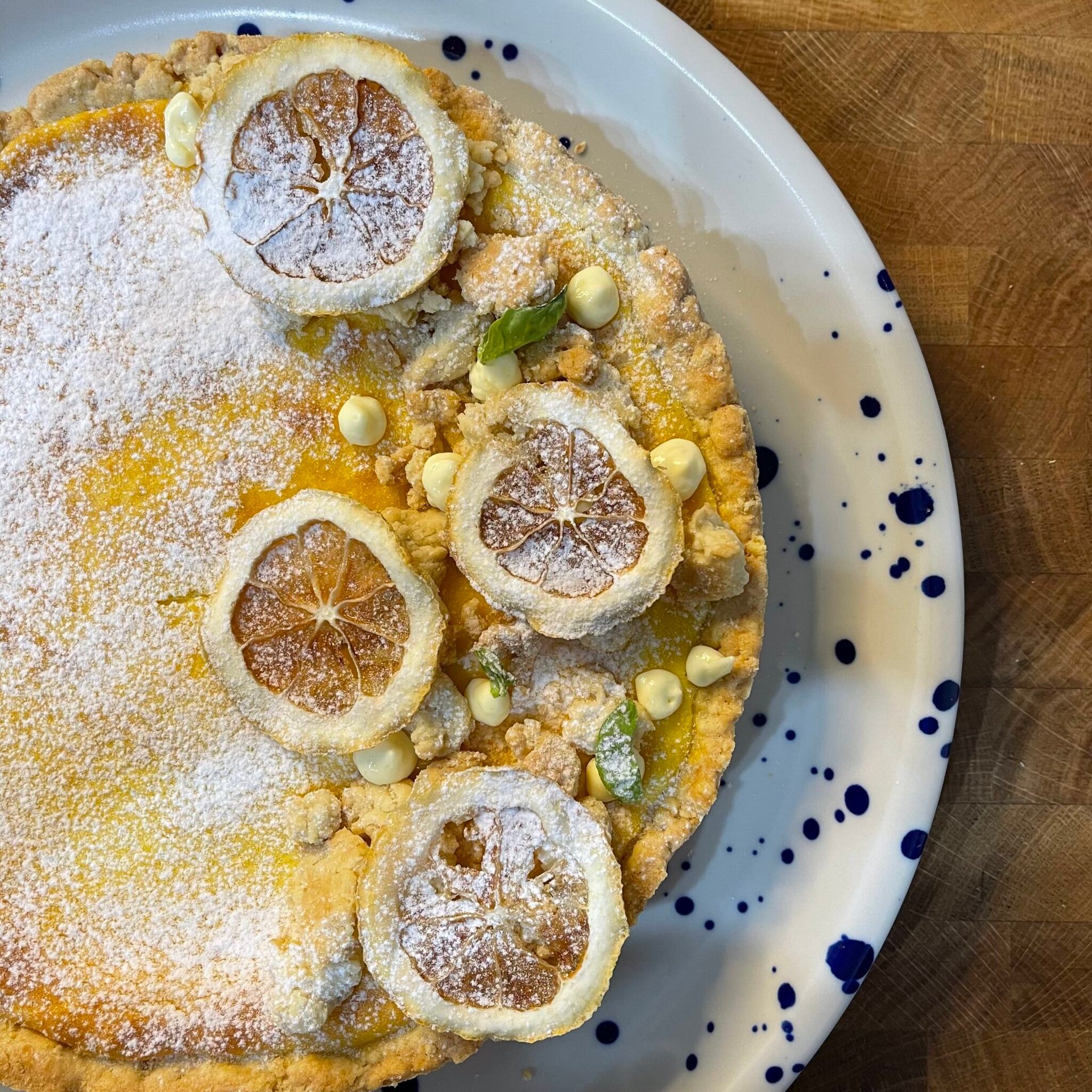 Un piatto bianco sormontato da una torta con fette di limone e zucchero a velo