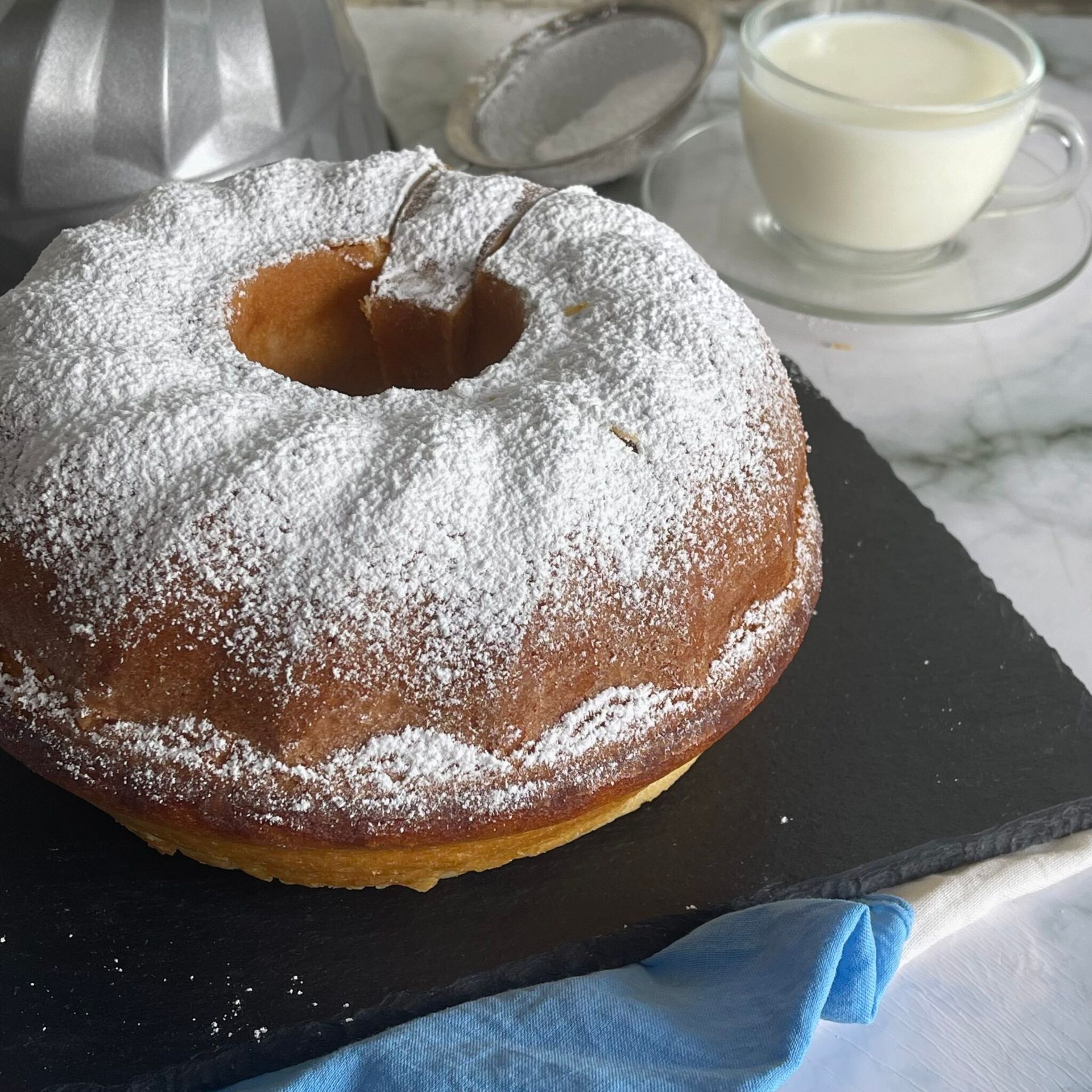 Una ciambella ricoperta di zucchero a velo accanto a una tazza di latte