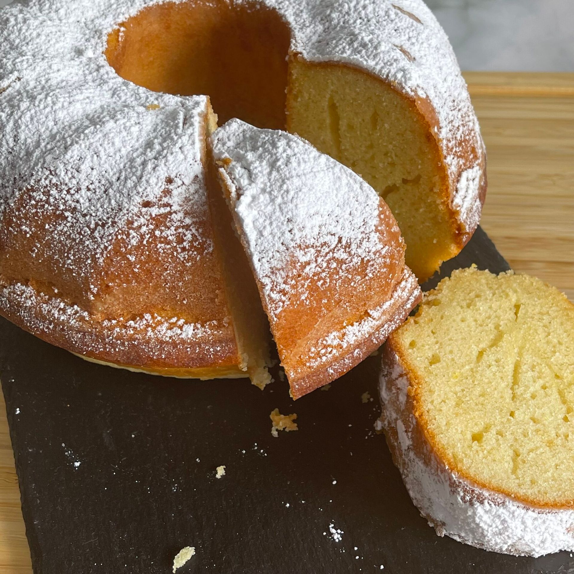 Una ciambella con zucchero a velo e una fetta tagliata fuori